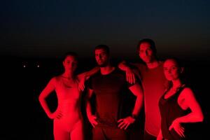 Diverse Athletes Unwind. Post-Marathon Rest Under Red Nighttime Glow. photo