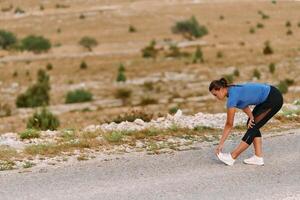 Determined Female Athlete Stretching After an Intense Run Through Rugged Mountain Terrain. photo