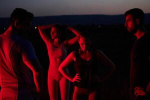 Diverse Athletes Unwind. Post-Marathon Rest Under Red Nighttime Glow. photo