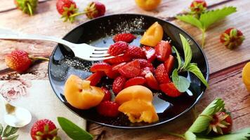 vers fruit salade van rijp aardbeien en abrikozen, Aan een licht houten tafel video