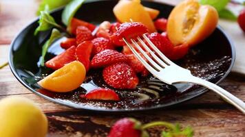 färsk frukt sallad av mogen jordgubbar och aprikoser, på en ljus trä- tabell video