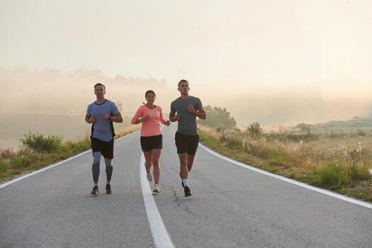 A group of friends, athletes, and joggers embrace the early morning hours as they run through the misty dawn, energized by the rising sun and surrounded by the tranquil beauty of nature photo
