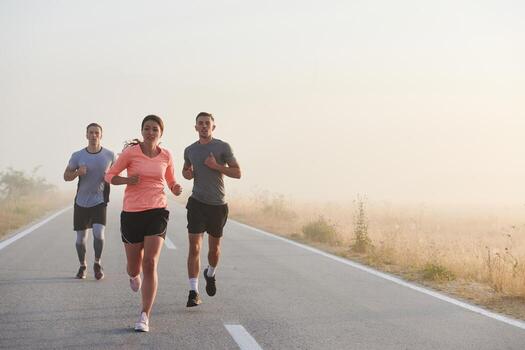 A group of friends, athletes, and joggers embrace the early morning hours as they run through the misty dawn, energized by the rising sun and surrounded by the tranquil beauty of nature photo
