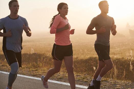 A group of friends, athletes, and joggers embrace the early morning hours as they run through the misty dawn, energized by the rising sun and surrounded by the tranquil beauty of nature photo