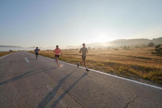 A group of friends, athletes, and joggers embrace the early morning hours as they run through the misty dawn, energized by the rising sun and surrounded by the tranquil beauty of nature photo