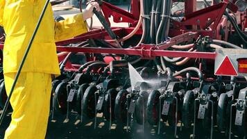 Waschen von großformatig landwirtschaftlich Maschinen. Reinigung das Sämaschine nach Arbeit im das Feld. ein Arbeiter wäscht ein landwirtschaftlich Maschine mit Wasser unter Druck. video