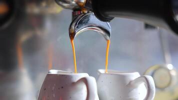 Pouring the coffee flow from the machine into two cups. Close up. Preparation of hot expresso. Concept of drinking roasted black coffee in the morning. video