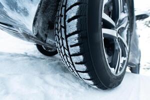 Car with winter tires on snowy road, closeup view photo