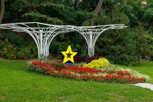 yellow star next to a flowerbed of flowers on green grass photo