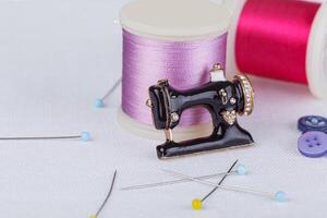 still life of a skein of thread for sewing, needles, buttons, sewing machine on a white background photo