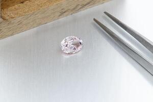 macro mineral faceted stone Morganite with tweezers on a gray background photo