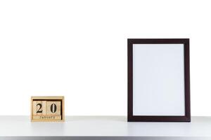 Wooden calendar 20 January with frame for photo on white table and background