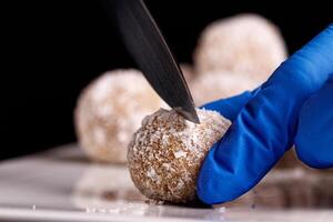 Beautiful sweets with coconut are cut with a knife on a white plate on a black background photo