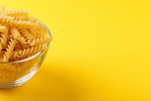 Different types and shapes of dry italian pasta on a yellow background photo