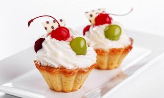 Beautiful cream cakes with cherries and grapes on a plate on a white background photo