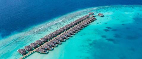 Maldives paradise water villas. Tropical aerial landscape, seascape with long jetty, water villas with amazing sea and lagoon ocean beach, tropical nature. Exotic tourism destination, summer vacation photo