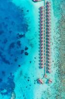 Maldives paradise water villas. Tropical aerial landscape, seascape with long jetty, water villas with amazing sea and lagoon ocean beach, tropical nature. Exotic tourism destination, summer vacation photo