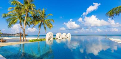 maravilloso paisaje, nadando piscina azul cielo con nubes tropical recurso hotel en Maldivas. fantástico relajarse y pacífico vibras, sillas, tumbonas debajo paraguas y palma hojas. lujo viaje vacaciones foto