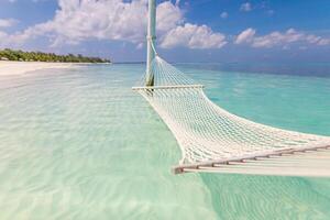 Wonderful beach panorama as summer landscape with beach swing or hammock and white sand and calm sea as beach banner. Panoramic beach scene vacation and summer holiday concept. Boost up color process photo