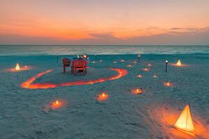 Table setup for wedding ceremony on sunset beach. Romantic destination dining, couple anniversary romance celebration. Love arrangement togetherness dinner on island shore. Amazing sky sea view photo