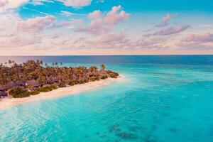 Aerial sunset panoramic landscape luxury tropical resort villas. Beautiful island beach orange sunrise sea sky. Amazing bird eyes panorama Maldives paradise tropical bay. Exotic summer vacation photo