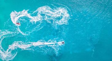 Aerial view of water extreme action sport, summer sea, close to luxury tropical resort . Fly board in ocean lagoon, freedom fun as summer recreational activity. Flyboard view from drone photo