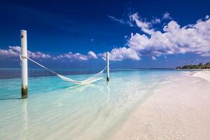 Wonderful beach panorama as summer landscape with beach swing or hammock and white sand and calm sea as beach banner. Panoramic beach scene vacation and summer holiday concept. Boost up color process photo