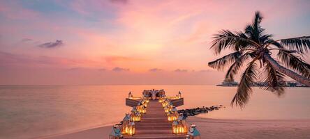 cena romántica en la playa con puesta de sol, velas con hojas de palma y cielo y mar al atardecer. vista increíble, paisaje de luna de miel o cena de aniversario. isla exótica horizonte nocturno, romance para una pareja foto