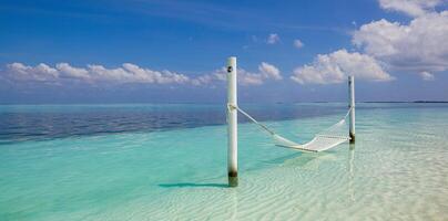 Wonderful beach panorama as summer landscape with beach swing or hammock and white sand and calm sea as beach banner. Panoramic beach scene vacation and summer holiday concept. Boost up color process photo