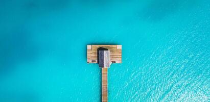 Aerial view of Maldives island, luxury water villas resort and wooden pier. Beautiful sky and ocean lagoon beach background. Summer vacation holiday and travel concept. Paradise aerial landscape pano photo