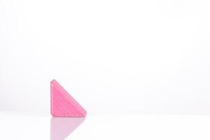 Wooden triangle of pink color on a white background photo