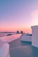 White architecture in romantic sunset light on Santorini island, Greece. Couple chairs on caldera terrace with sea view, beautiful colorful skyline sky view. Honeymoon panoramic travel background photo