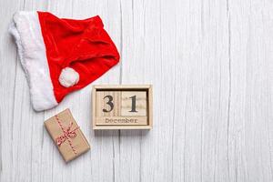 christmas hat, gift and wooden calendar 31 december on a wooden background photo