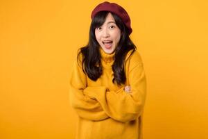 Young Asian woman in her 30s, confidently crossing her arms on her chest, wearing a yellow sweater and red beret against a yellow background. photo