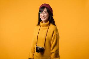 en su elegante estudio, un joven asiático mujer, poniéndose un amarillo suéter y rojo boina, toma un retro retrato utilizando su amado cámara, recordativo de 20s y 30s nostalgia. foto