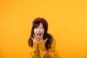 Radiant in a yellow sweater and red beret, a young Asian woman laughs with sheer delight against a cheerful yellow backdrop. photo