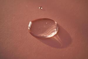 Beautiful volumetric drop of cosmetic product on a pink background. photo