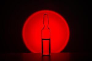 ampolla para inyección en contra el antecedentes de un brillante rojo círculo. foto