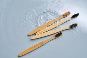 Natural bamboo toothbrushes in water on a blue background. photo