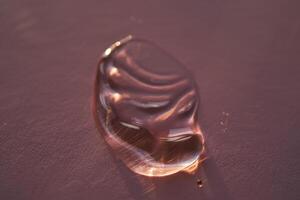 Beautiful volumetric drop of cosmetic product on a dark purple background. photo