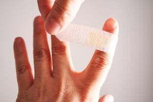 Applying an adhesive plaster to a finger. Close-up. photo