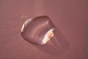 Beautiful volumetric drop of cosmetic product on a pink background. photo