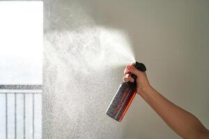 un mujer mano aerosoles un aire ambientador en un habitación. foto