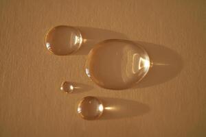 hermosa volumétrico gotas de cosmético producto en un beige antecedentes. foto