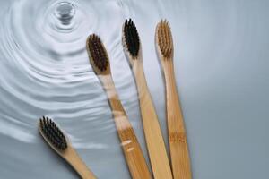 Natural bamboo toothbrushes in water on a blue background. photo