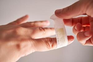 Applying an adhesive plaster to a finger. Close-up. photo
