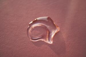 Beautiful volumetric drop of cosmetic product on a pink background. photo