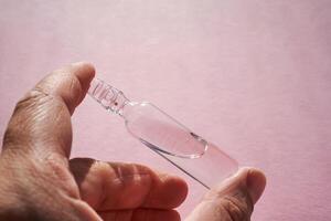 Ampoule for injection with medicines on a pink background in hand. photo