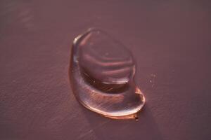 Beautiful volumetric drop of cosmetic product on a dark purple background. photo