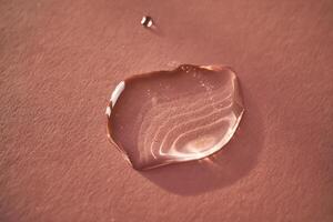 Beautiful volumetric drop of cosmetic product on a pink background. photo